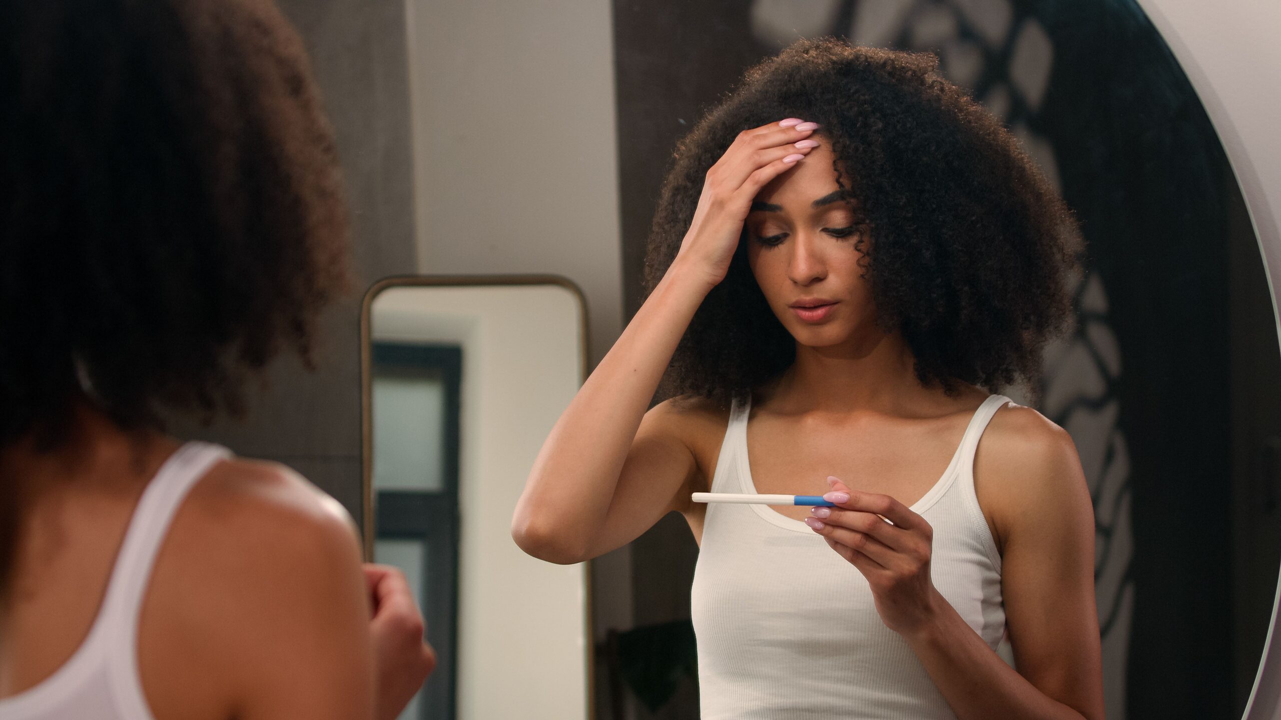 woman in bathroom looking at positive pregnancy test