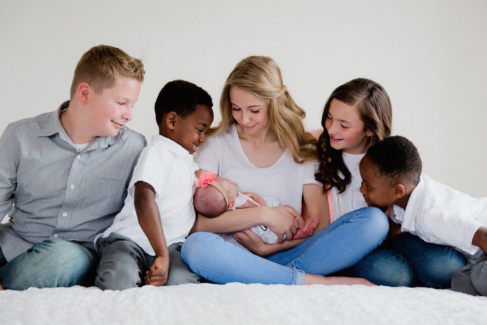 Mother holds child as four other children admire the baby
