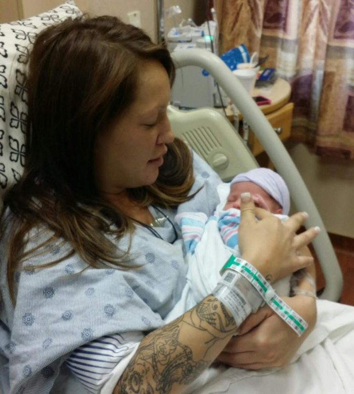 Mother holds her new child in hospital bed.