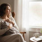 woman holding her baby while sitting in a chair